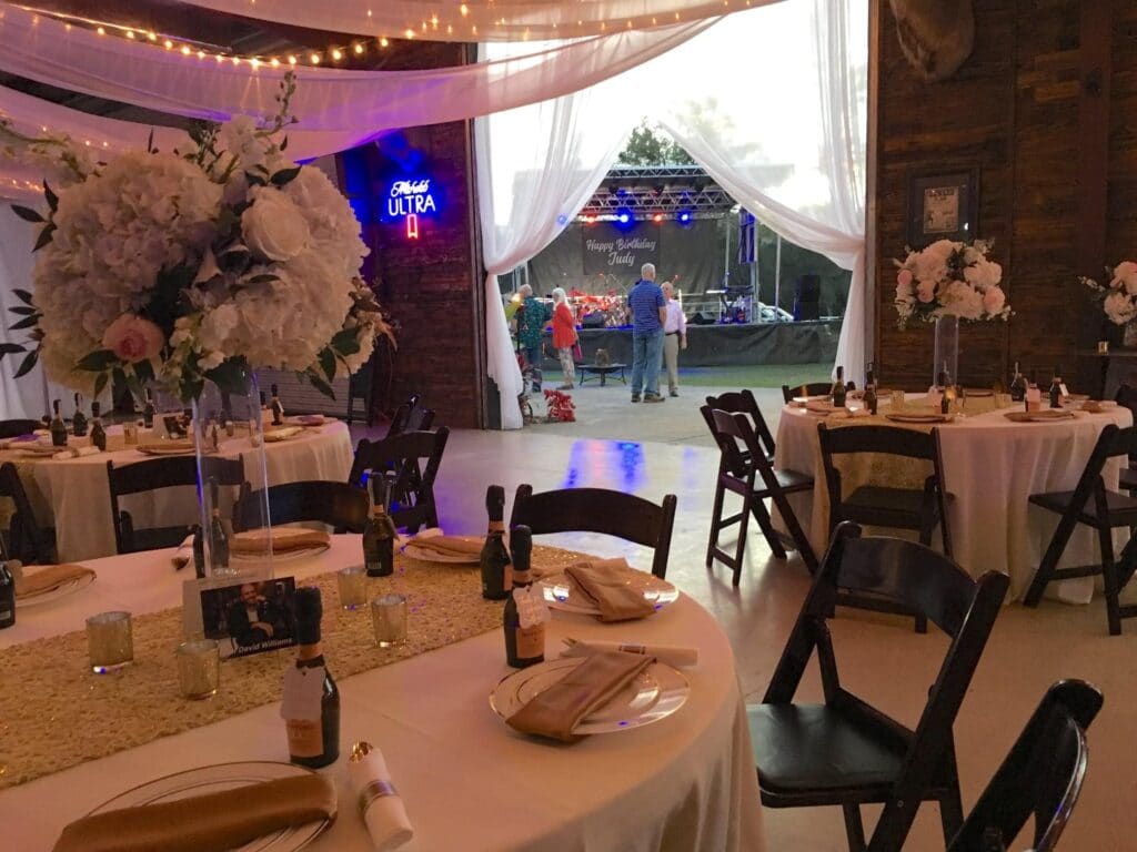 indoor wedding reception with white tables, black chairs, and market lights